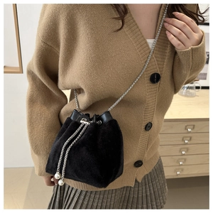 Detail of black plush bucket bag with silver chain strap and pearl drawstring tassels