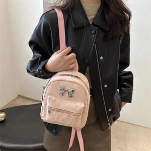 Mini sac à dos en velours rose avec détail papillon porté par un mannequin en style urbain