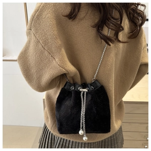 Detail of plush black bucket bag with silver chain and pearl drawstring on model