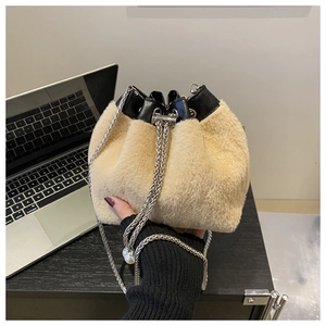 Detail of apricot plush bucket bag with black leather trim and pearl chain strap
