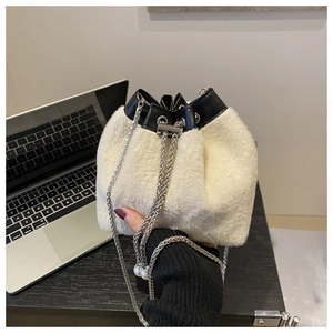 Detail showing plush white faux fur bucket bag with black leather trim and pearl chain