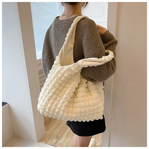 Detailed view of white popcorn texture tote bag worn on shoulder by a model