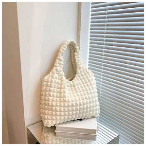 Detail showing white popcorn fabric texture on a minimalist shoulder bucket bag