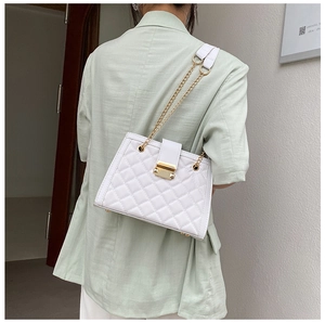 Detailed side view of white quilted shoulder bag with gold chain strap on mint blazer