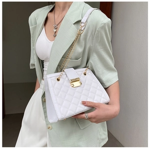 Close-up of white quilted shoulder bag featuring gold chain strap and metal lock detail
