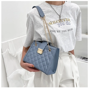 Detail of blue quilted leather shoulder bag with gold chain strap and metal buckle
