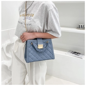 Detail view of blue quilted shoulder bag with chain strap and gold hardware clasp