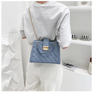 Detail shot of blue quilted shoulder bag with golden chain and metallic buckle closure