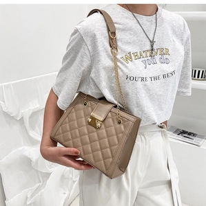 Detail of khaki quilted shoulder bag featuring gold chain strap and metallic buckle
