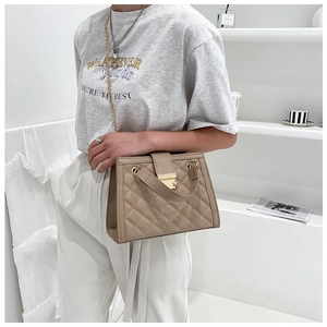 Close-up of beige quilted shoulder bag with gold square lock and metal chain strap