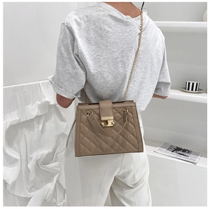 Close-up of khaki quilted leather texture with gold-tone metal chain and twist-lock