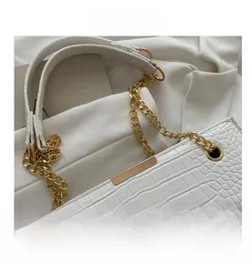 Close-up of white crocodile pattern tote bag with gold chain and metal hardware