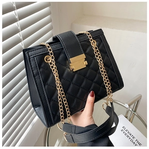 Detail of black quilted leather handbag with gold chain strap and elegant metal clasp