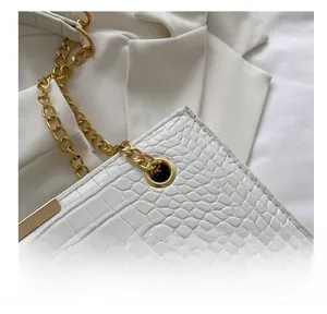 Macro shot of white croc-embossed leather tote bag with gold chain strap detail