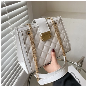 Detail of white quilted leather bag with gold buckle lock and metal chain strap