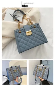 Detail of blue quilted chain shoulder bag with gold metal clasp and leather handle