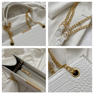Detail of white crocodile texture tote bag showing gold chain strap and metal hardware