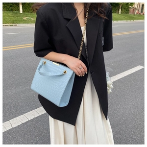 Detail of light blue crocodile embossed leather tote bag with elegant gold chain strap