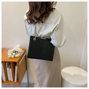 Close-up of black crocodile pattern shoulder bag with elegant gold chain strap