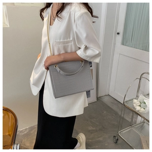 Detail of grey crocodile embossed leather tote bag with elegant gold chain shoulder strap