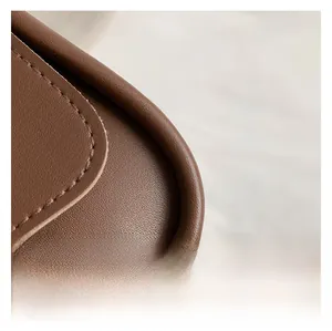 Macro detail of the smooth brown leather corner and neat stitching on a small square bag