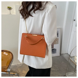 Detail view of the orange faux leather bag showing crocodile texture and gold chain strap