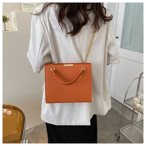 Detailed view of an orange crocodile pattern tote bag with golden chain and metal trim