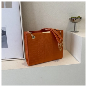 Detailed view of orange crocodile texture and gold chain on the retro tote bag