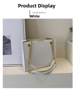 Detail view of white crocodile embossed tote bag with gold chain strap and metal trim