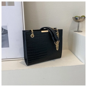 Detail of vintage black crocodile embossed tote with gold metal buckle and chain strap