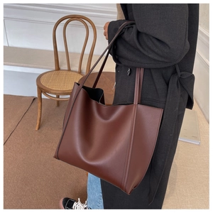 Vue latérale d'un grand sac cabas vintage marron foncé porté par un mannequin