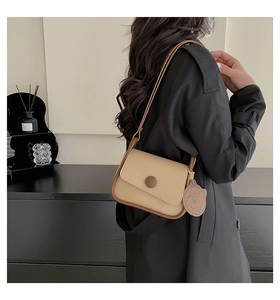 Detail of color-block mini shoulder bag with brown bear charm on black coat