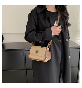 Detail of beige faux leather crossbody bag with brown trim and cute bear charm pendant