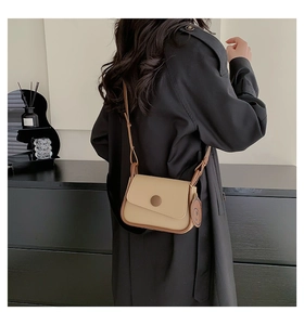 Detailed back view of a khaki crossbody flap bag worn by a model in a minimalist setting