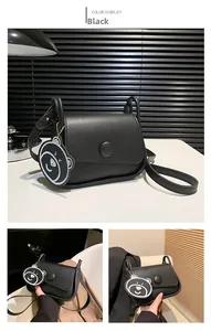 Detail of black matte leather crossbody bag featuring a round buckle and cute bear charm