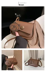 Detailed view of brown matte leather shoulder bag with cute bear charm and round buckle