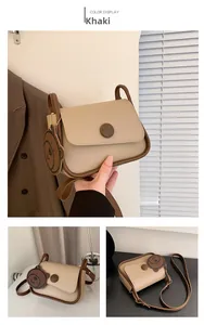 Detail view of khaki crossbody square bag with brown trim and cute bear charm