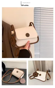Detail view of cream leather crossbody bag with brown trim and cute bear charm