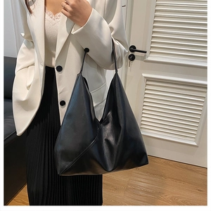 Detailed view of black minimalist tote bag on shoulder with triangular stitching design