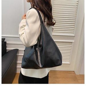 Macro detail of soft black faux leather tote bag showing smooth texture and spacious design
