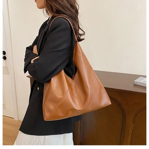 Caramel brown leather hobo tote bag for women worn over shoulder with wide strap