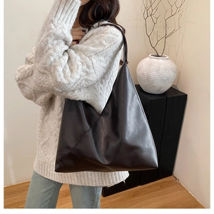 Detail of a minimalist dark brown geometric tote bag made of glossy PU leather material