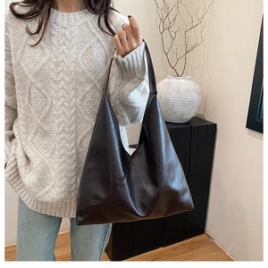 Detail of a minimalist dark brown tote bag showing supple leather texture and carry handle