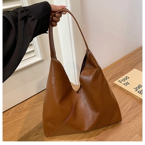Detail view of large caramel brown leather tote bag with glossy finish and wide shoulder strap