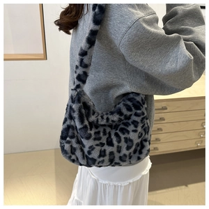 Detail view of a soft grey leopard print plush shoulder bag worn by a model
