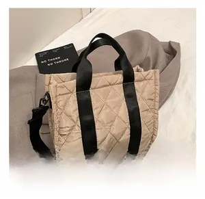 Detail showing beige quilted nylon texture and black wide shoulder straps of the tote bag