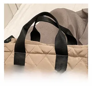 Close-up of a quilted nylon tote bag featuring wide black handles and large diamond stitching