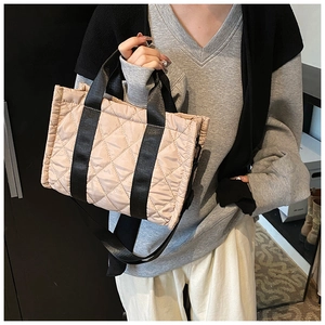 Dettaglio della borsa tote beige trapuntata con motivo a rombi e manici in tela nera