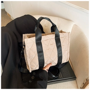 Dettaglio borsa shopper trapuntata beige con manici neri su sedia in stile minimal