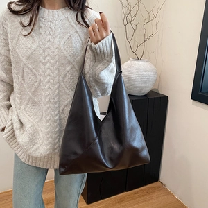 Minimalist large brown leather hobo shoulder bag styled for women in a chic indoor setting